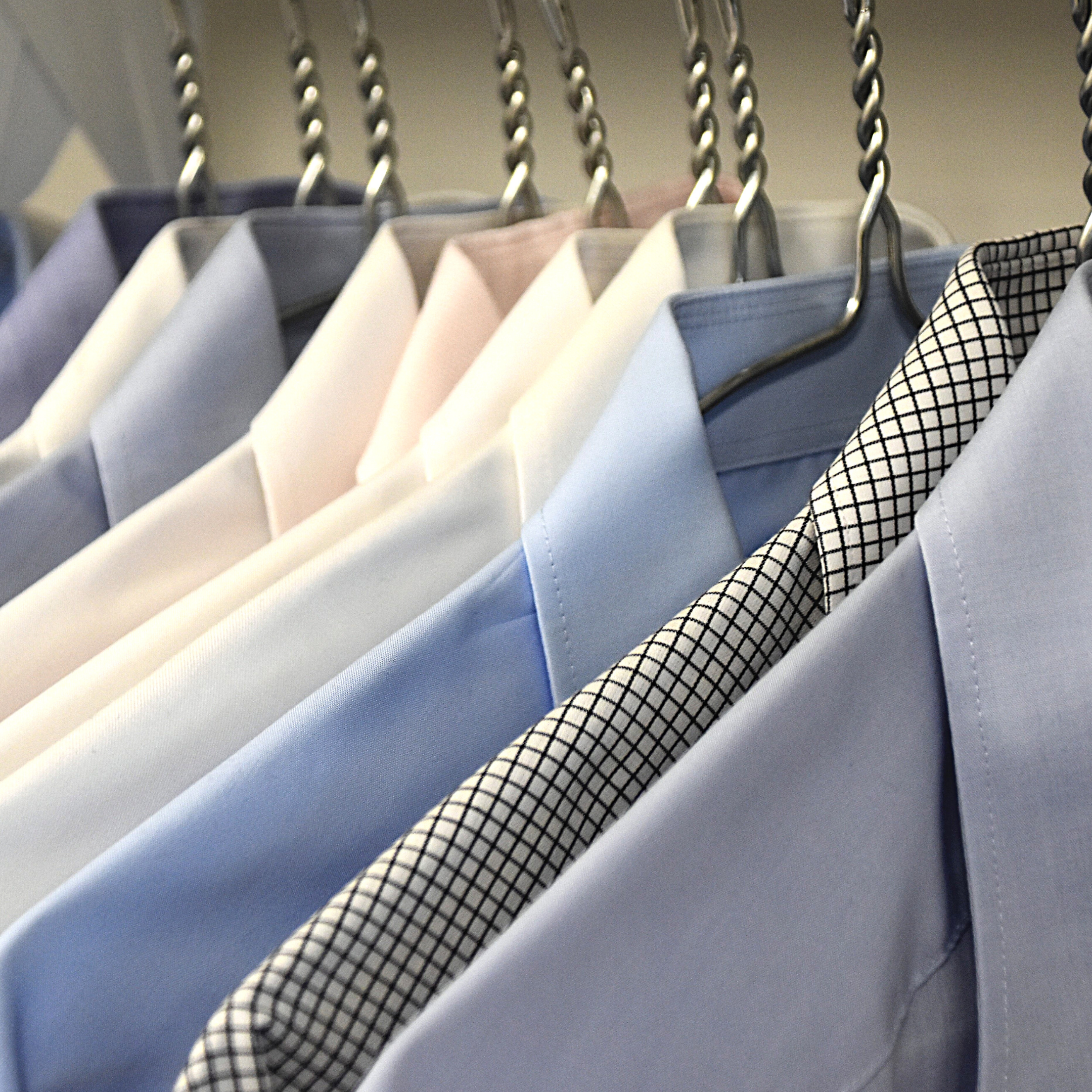 four striped dress shirts hanging from wooden clothes hangers